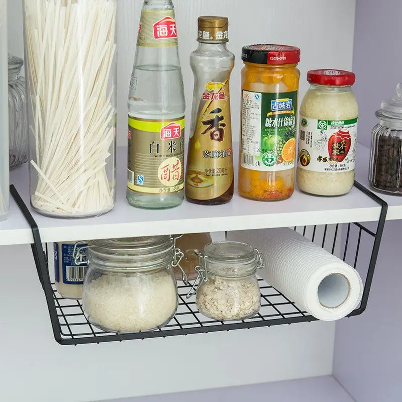 Kitchen shelf with various food items and a wire rack holding jars and a roll of paper towels.