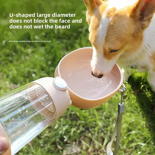 Dog drinking water from a portable pet water bottle and bowl set on grass.